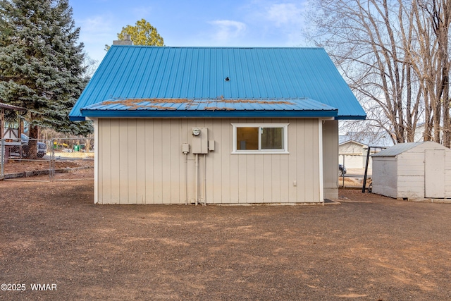 exterior space with metal roof, fence, a chimney, and an outdoor structure