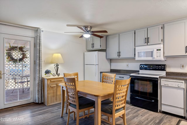 kitchen with a ceiling fan, dark countertops, white appliances, and wood finished floors