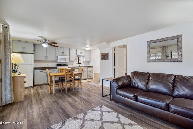 living room featuring dark wood-style floors and a ceiling fan