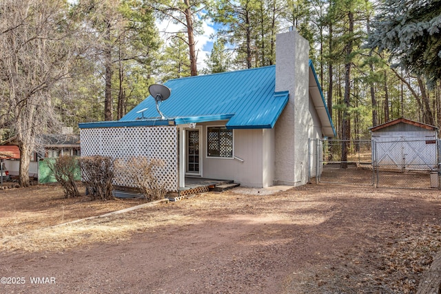 exterior space with metal roof, an outdoor structure, a chimney, and fence