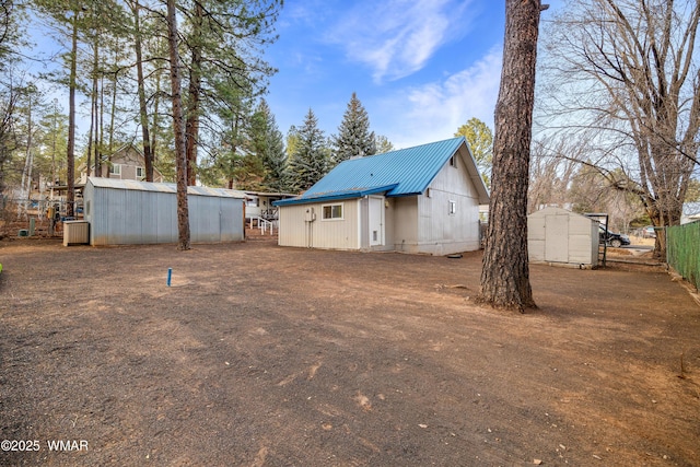 back of house featuring a storage shed, metal roof, an outdoor structure, and fence