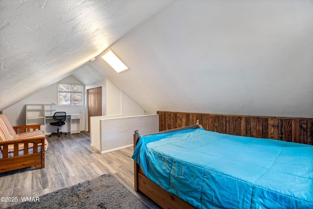 bedroom with light wood-style floors, lofted ceiling, and wood walls