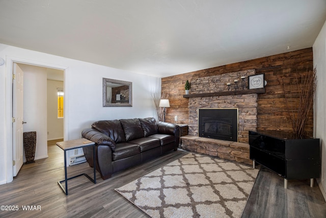 living area with a stone fireplace and wood finished floors