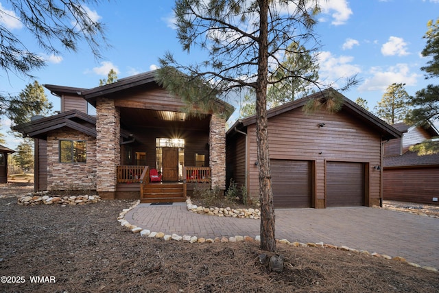 view of front facade featuring decorative driveway, stone siding, a garage, and a porch