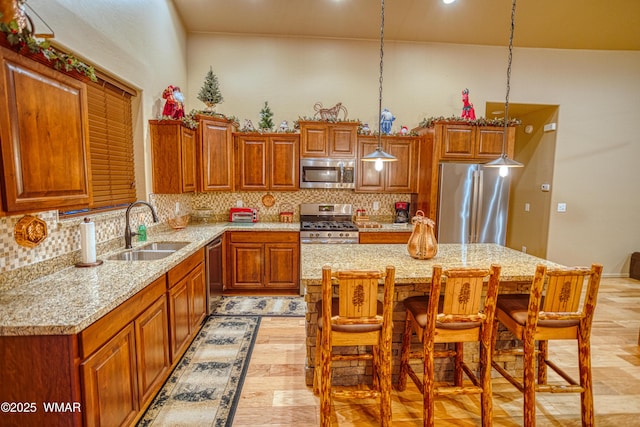 kitchen featuring light stone countertops, a breakfast bar, a sink, stainless steel appliances, and backsplash