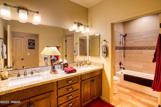 bathroom featuring shower / tub combination, toilet, wood finished floors, and a sink