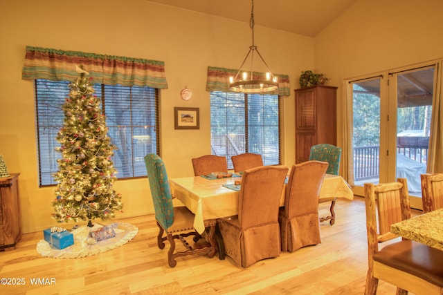 dining area with a chandelier, light wood-style flooring, and vaulted ceiling