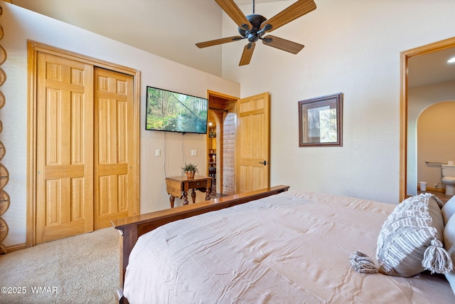 bedroom featuring carpet floors, a closet, a ceiling fan, and arched walkways