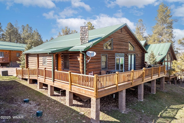 rear view of house featuring metal roof, a deck, log siding, and a chimney