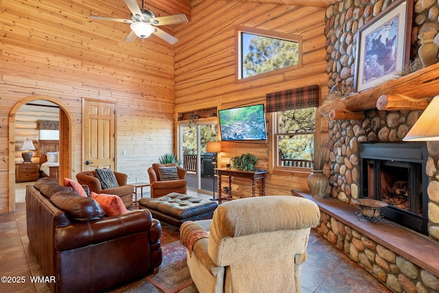 living area with ceiling fan, wooden ceiling, arched walkways, a fireplace, and high vaulted ceiling