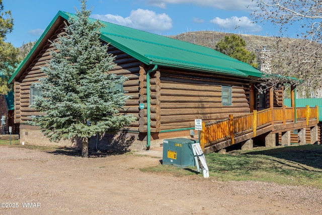 view of side of home featuring log exterior, a deck, and metal roof
