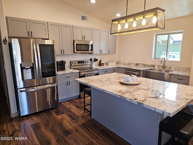 kitchen featuring a kitchen breakfast bar, a sink, appliances with stainless steel finishes, visible vents, and gray cabinets