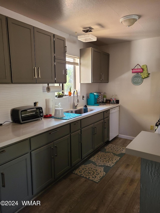 kitchen featuring dark wood finished floors, tasteful backsplash, light countertops, a sink, and dishwasher