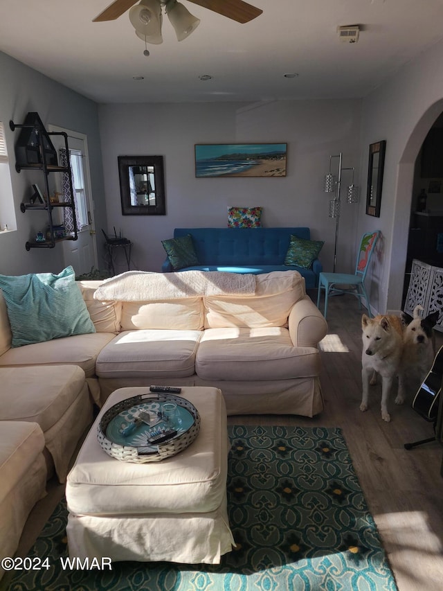 living room with ceiling fan, arched walkways, and wood finished floors