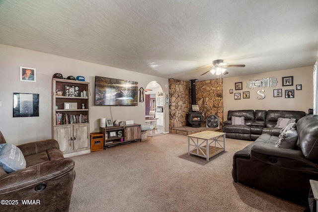 389 E 3rd St, Eagar, AZ 85925 - living room featuring arched walkways, carpet flooring, ceiling fan, a wood stove, and a textured ceiling