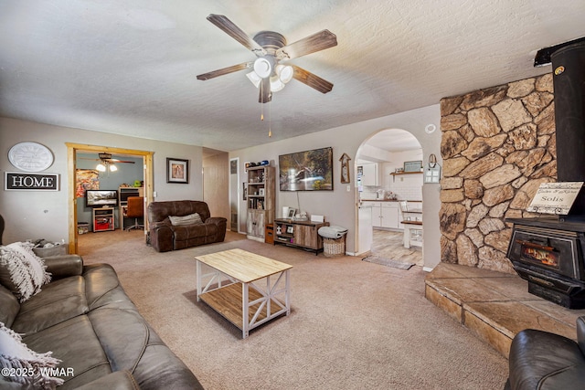 389 E 3rd St, Eagar, AZ 85925 - carpeted living room with a wood stove, ceiling fan, arched walkways, and a textured ceiling