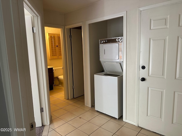 washroom featuring stacked washer / drying machine, laundry area, and light tile patterned flooring