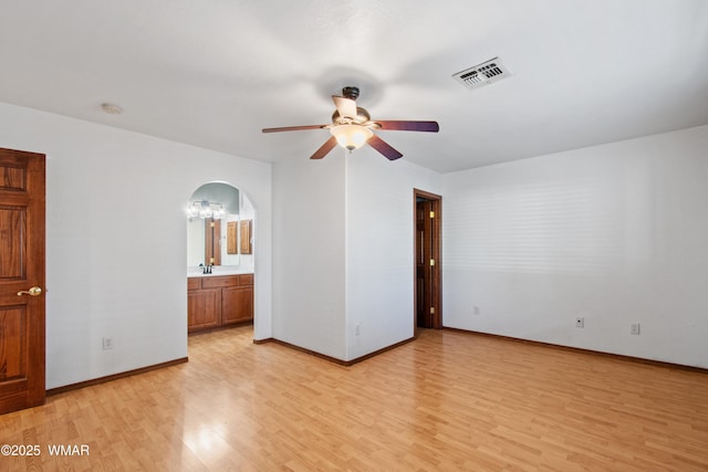 677 Fox Ln, Lakeside, AZ 85929 - unfurnished bedroom with light wood finished floors, arched walkways, baseboards, a chandelier, and a sink