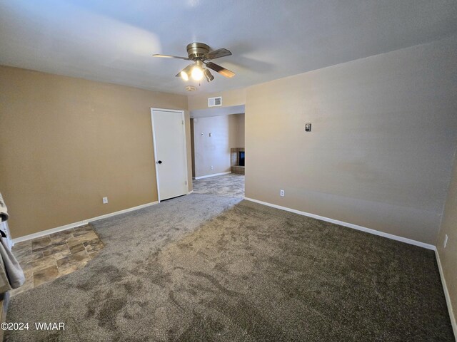 spare room with carpet floors, visible vents, ceiling fan, and baseboards