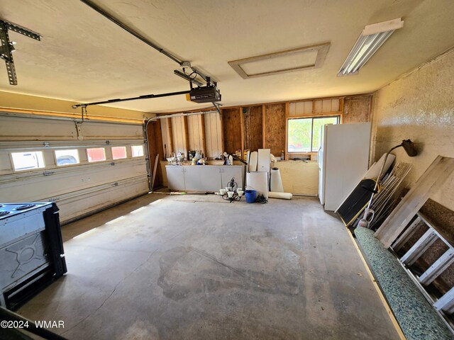 garage with a garage door opener and freestanding refrigerator