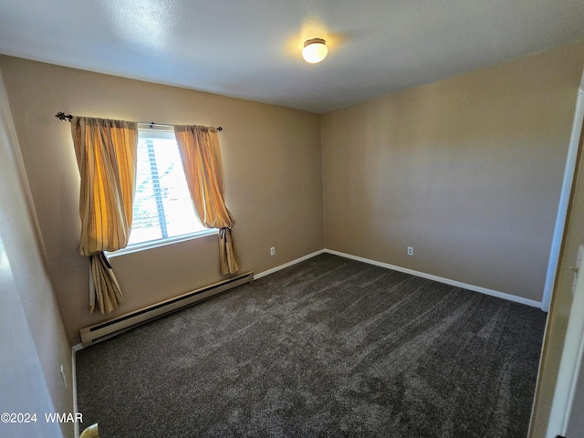 empty room with a baseboard heating unit, dark colored carpet, and baseboards