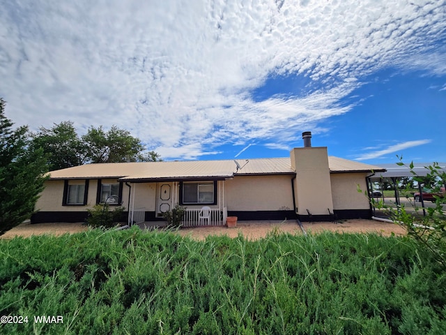 rear view of house with a chimney and stucco siding