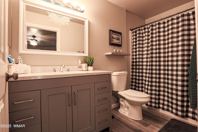 full bathroom with wood finished floors, vanity, toilet, curtained shower, and ceiling fan