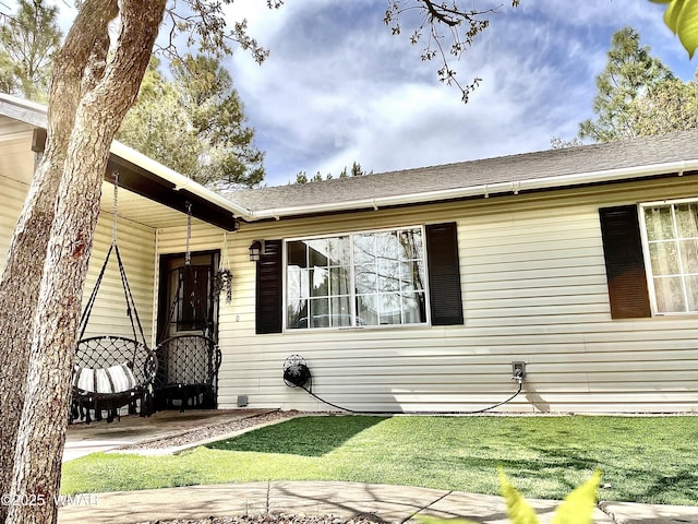 view of front of house featuring a front lawn and a shingled roof