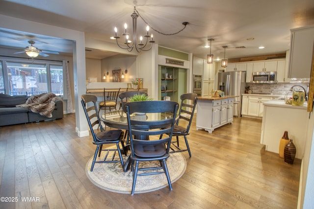 dining room featuring ceiling fan with notable chandelier, light wood-style flooring, baseboards, and recessed lighting
