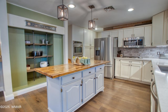 kitchen with wood counters, wood finished floors, stainless steel appliances, and white cabinets