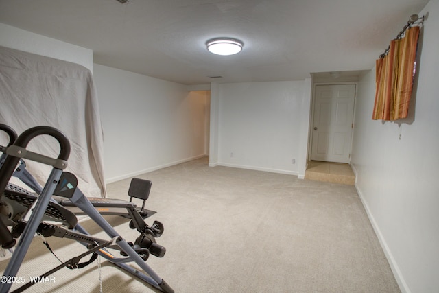 workout room featuring light carpet and baseboards
