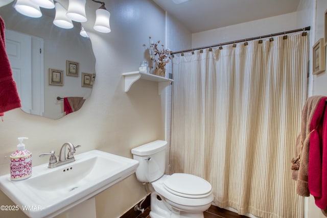 full bathroom with a shower with curtain, toilet, and a sink