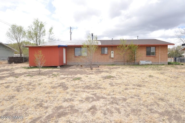 rear view of property featuring brick siding and fence
