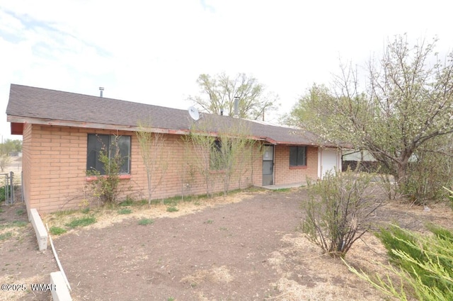 single story home with brick siding, a shingled roof, and driveway