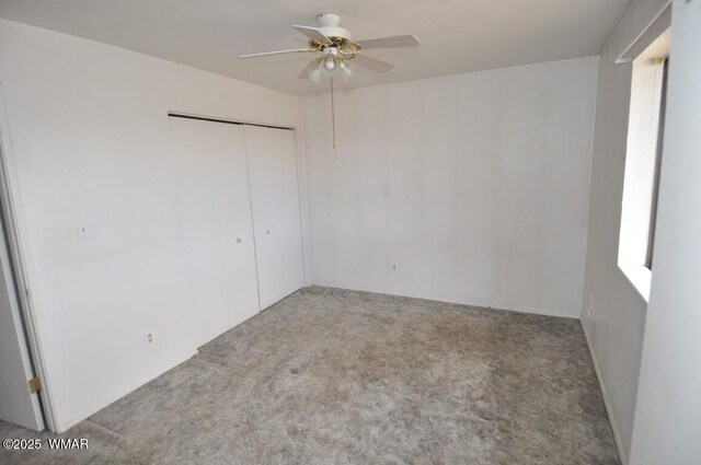 unfurnished bedroom featuring carpet flooring, a closet, and a ceiling fan