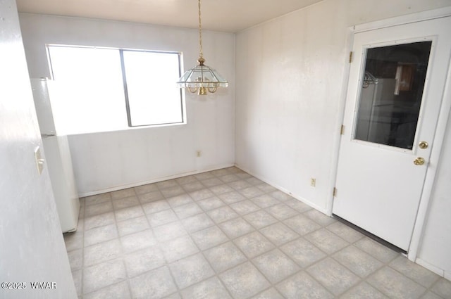 unfurnished dining area featuring a chandelier and light floors