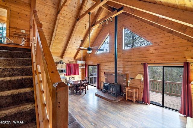living area featuring a wood stove, wooden ceiling, stairs, and beam ceiling
