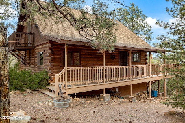 view of front of property featuring a deck, log exterior, and roof with shingles