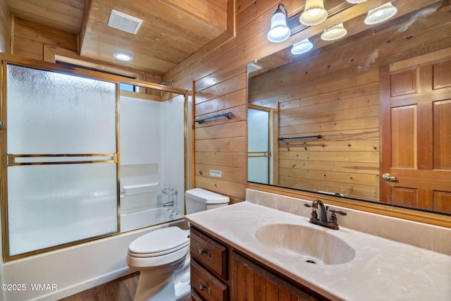 bathroom with shower / bath combination with glass door, visible vents, toilet, wooden walls, and vanity