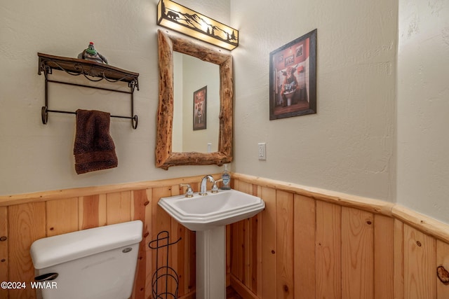bathroom featuring toilet, a sink, and wainscoting