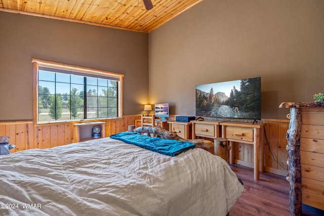 bedroom featuring vaulted ceiling, wood finished floors, wainscoting, wooden ceiling, and wood walls