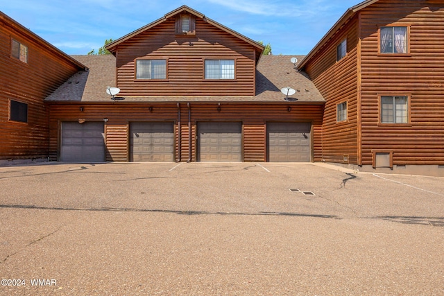 view of front of property featuring faux log siding and a shingled roof
