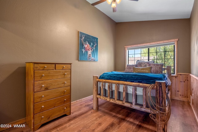 bedroom featuring wainscoting, baseboards, a ceiling fan, and wood finished floors