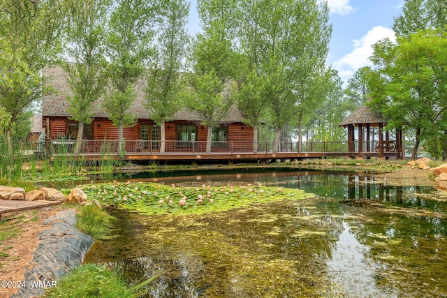 exterior space with roof with shingles, a water view, a gazebo, and log veneer siding