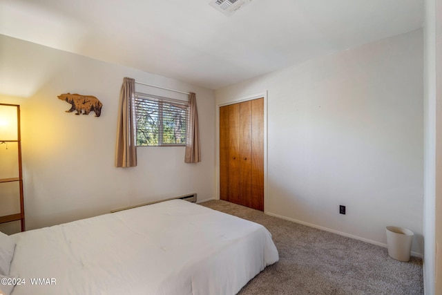 bedroom with a baseboard heating unit, carpet floors, visible vents, baseboards, and a closet