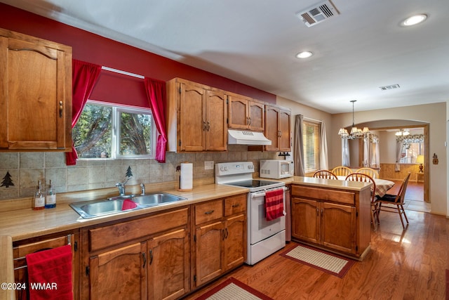 kitchen featuring decorative light fixtures, light countertops, a sink, white appliances, and under cabinet range hood