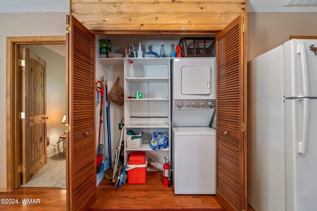 washroom featuring stacked washer / drying machine, laundry area, and wood finished floors