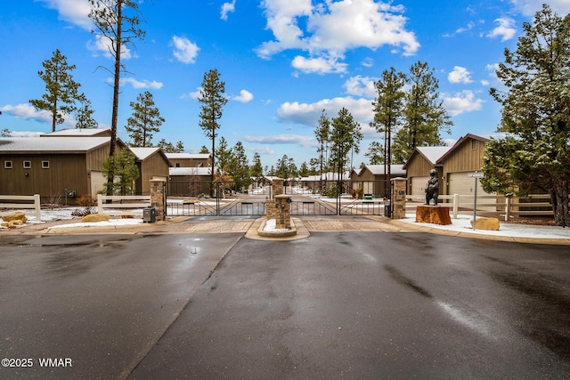 view of road featuring sidewalks, a gate, a residential view, and a gated entry
