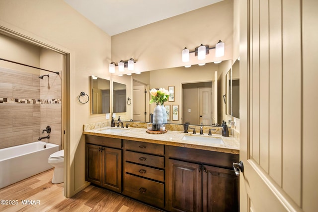 bathroom featuring double vanity, toilet, wood finished floors, and a sink