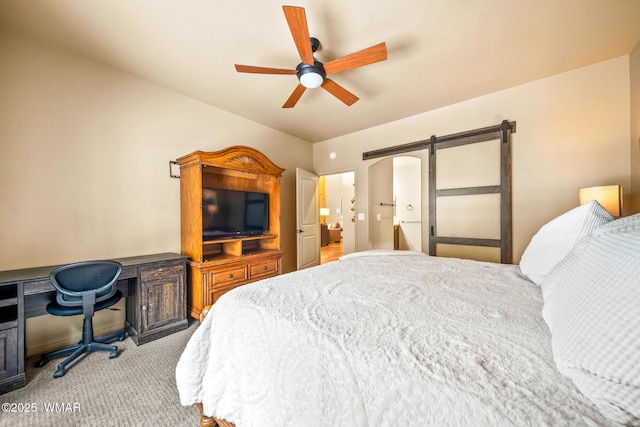carpeted bedroom with a barn door and ceiling fan